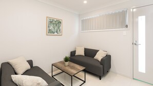 Un salon moderne avec un canapé gris, une table basse en bois et une petite plante en pot.