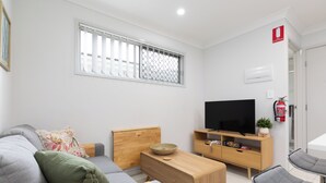 Una sala de estar moderna con un sofá gris, una mesa de centro de madera y un televisor de pantalla plana.