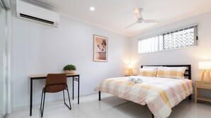 A bedroom with a bed, a desk, a chair, a window with blinds, a ceiling fan, and a wall-mounted air conditioner. - Clean 1 Bdr Apt w/ AC & Kitchen | Parking | 139F1 (Rocklea)