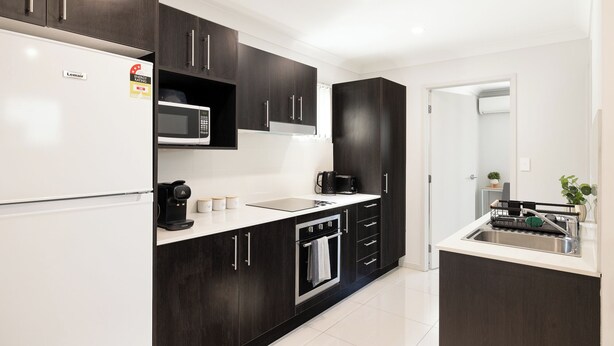 Una cucina moderna con mobili scuri, un forno a microonde integrato, una macchina da caffè e un lavello.
