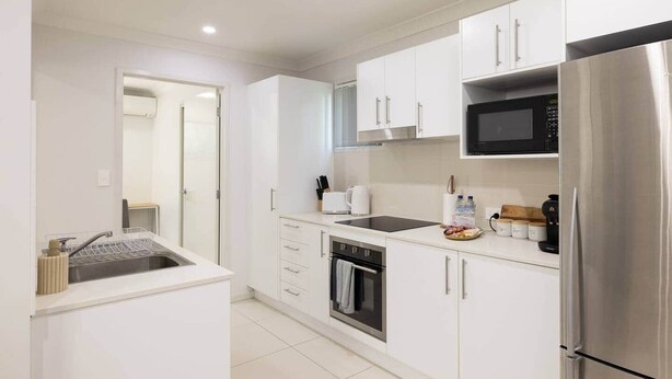 Una cocina moderna con armarios blancos, un refrigerador de acero inoxidable, un microondas y un lavavajillas.