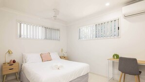Un dormitorio con cama, mesitas de noche, escritorio y silla.