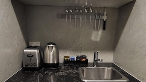 A compact kitchen with white cabinets, a stainless steel sink, a toaster, a kettle, and a microwave. - Jesmond Small Studio (Jesmond)