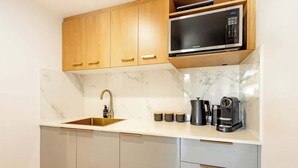 Una cocina moderna con microondas integrado, un lavamanos y una cafetera.
