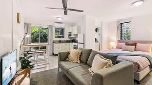 Une chambre moderne comprenant un lit, un canapé, une télévision et un coin cuisine.