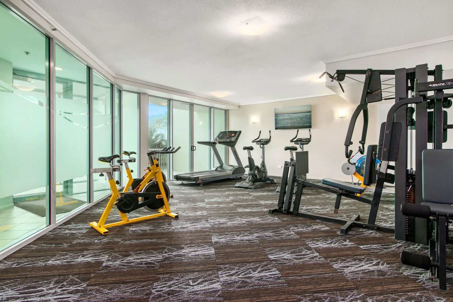 A gym with cardio machines, a bench press, and a weight machine.