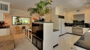 Een moderne keuken met witte kasten, een centraal eiland en een grote potplant.