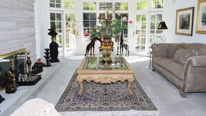 Een ruime woonkamer met een grote, sierlijke salontafel, een comfortabele bank en een decoratief vloerkleed.