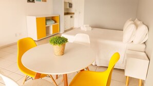 A modern room with a round table, yellow chairs, a white sofa, and a small potted plant. - Mares Suites by Angra Beach (Angra dos Reis)