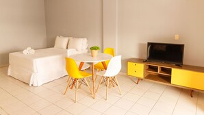 A bedroom with a bed, bedside table, TV, and a dining area with chairs and a table. - Mares Suites by Angra Beach (Angra dos Reis)