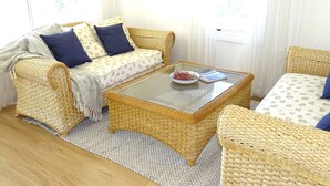 A cozy living room with wicker furniture, a glass coffee table, and a patterned sofa.