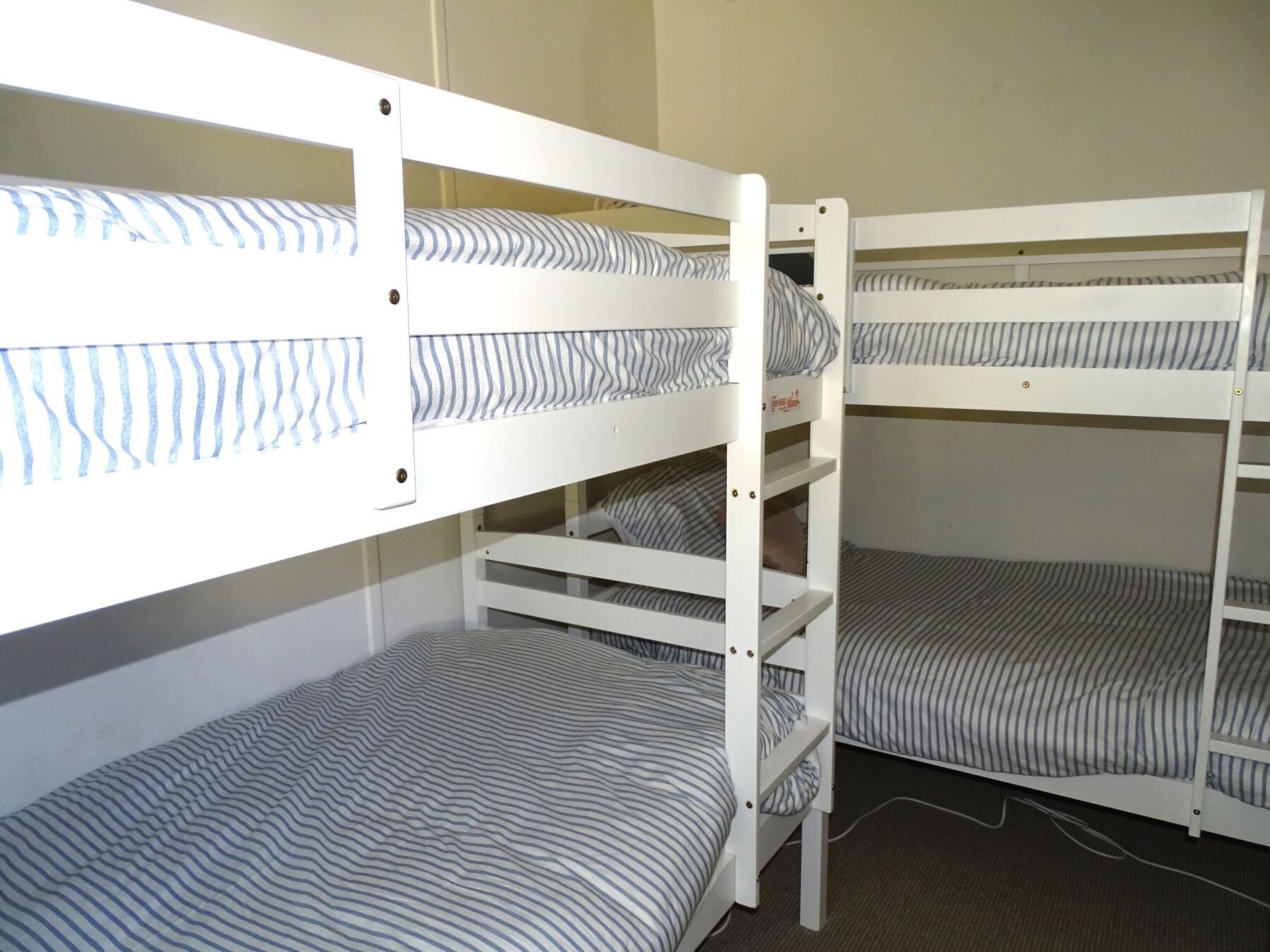 Dormitorio con literas, ropa de cama a rayas y piso alfombrado.