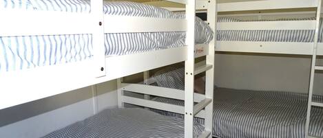 Dormitorio con literas, ropa de cama a rayas y piso alfombrado.