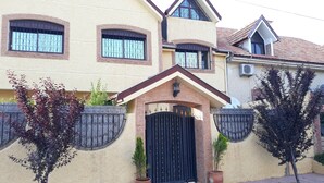 A two-story house with a black gate, potted plants, and a small balcony. - Cozy, Peaceful & Clean Studio Only 300 MAD (Ifrane)