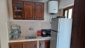 A compact kitchen with wooden cabinets, a stainless steel sink, a coffee maker, and a refrigerator. - Cozy, Peaceful & Clean Studio Only 300 MAD (Ifrane)