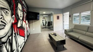 Una sala de estar moderna con un gran mural abstracto, un televisor de pantalla plana, un sofá gris y una mesa de centro.