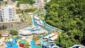 Un parque acuático con varias toboganes y piscinas, rodeado de follaje y edificios.