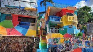 Un edificio colorido de varios pisos con patrones geométricos vibrantes y un hidrante amarillo en la base.