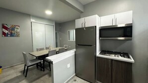 A compact kitchen with a refrigerator, microwave, and gas stove. - Reggaeton Vibes! Puerto Rico's Legend Suite, Just 4 mins from Crash Boat Beach (Aguadilla)