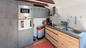 A compact kitchen with a built-in oven, a coffee maker, and a sink.