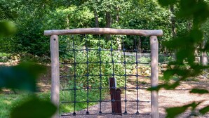 A wooden gate with a metal mesh fence in a wooded area.