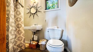A bathroom with a white sink, toilet, patterned shower curtain, and a decorative wall piece.