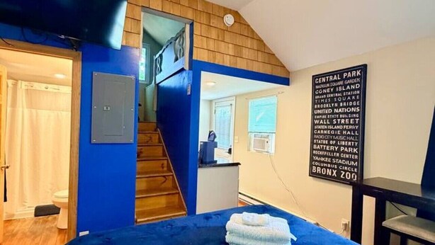 Un dormitorio con colcha azul, una escalera de madera y un cartel en la pared que enumera lugares emblemáticos de Central Park.