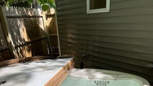 Jacuzzi al aire libre con terraza de madera y suelo de ladrillo.