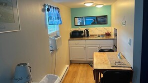 Cocina compacta con microondas, estufa y una pequeña mesa de comedor.