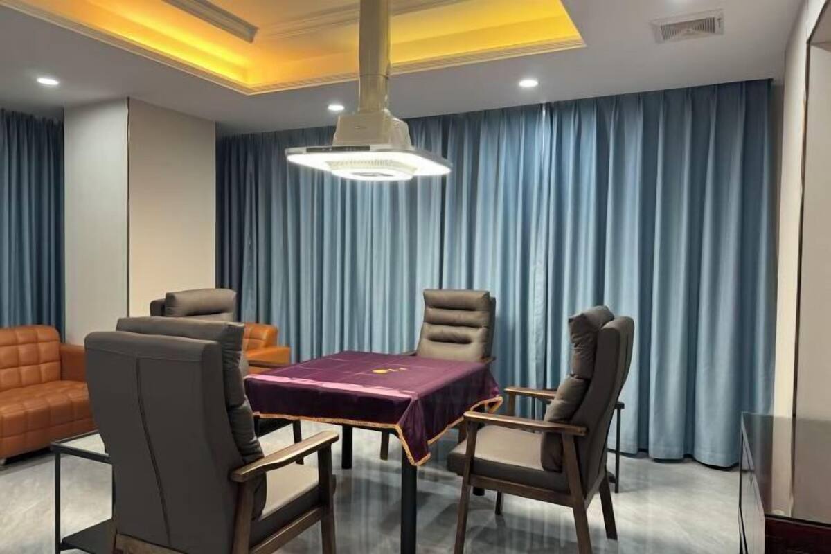 A modern room with a round table, four chairs, a sofa, and a large window with curtains.