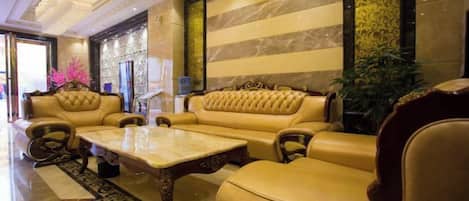A lobby with a sofa, armchairs, a coffee table, and a patterned rug.