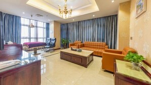 Ένας ευρύχωρος χώρος καθιστικού με ένα σετ καναπέ, ένα τραπεζάκι σαλονιού και ένα γραφείο με καρέκλα.