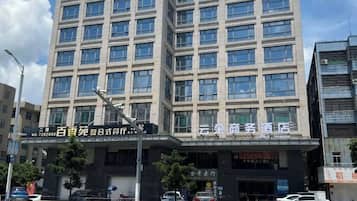 A multi-story building with a commercial ground floor, featuring a large sign with Chinese characters, multiple windows, and a few parked cars in front.
