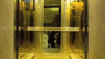An elevator with a reflective metallic interior and a person descending.
