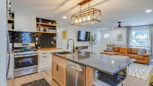 A modern kitchen with built-in appliances, a central island, and a dining area with a sofa. - Luxe 4-Bed Retreat w/ Game Room & Deck – 10 Min to Downtown (Nashville)
