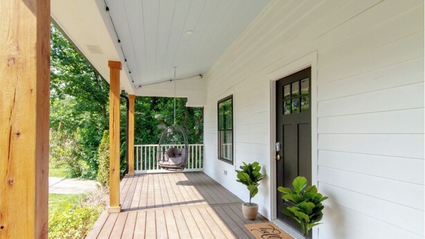 A wooden porch with a swing chair, potted plants, and a door. - Luxe 4-Bed Retreat w/ Game Room & Deck – 10 Min to Downtown (Nashville)