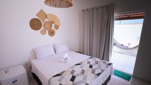 A hotel room with a bed, a small refrigerator, a woven wall decoration, and a view of the outside. - Beachfront House with Sea Views, Pool and Independent Suites Pet Friendly (Touros)