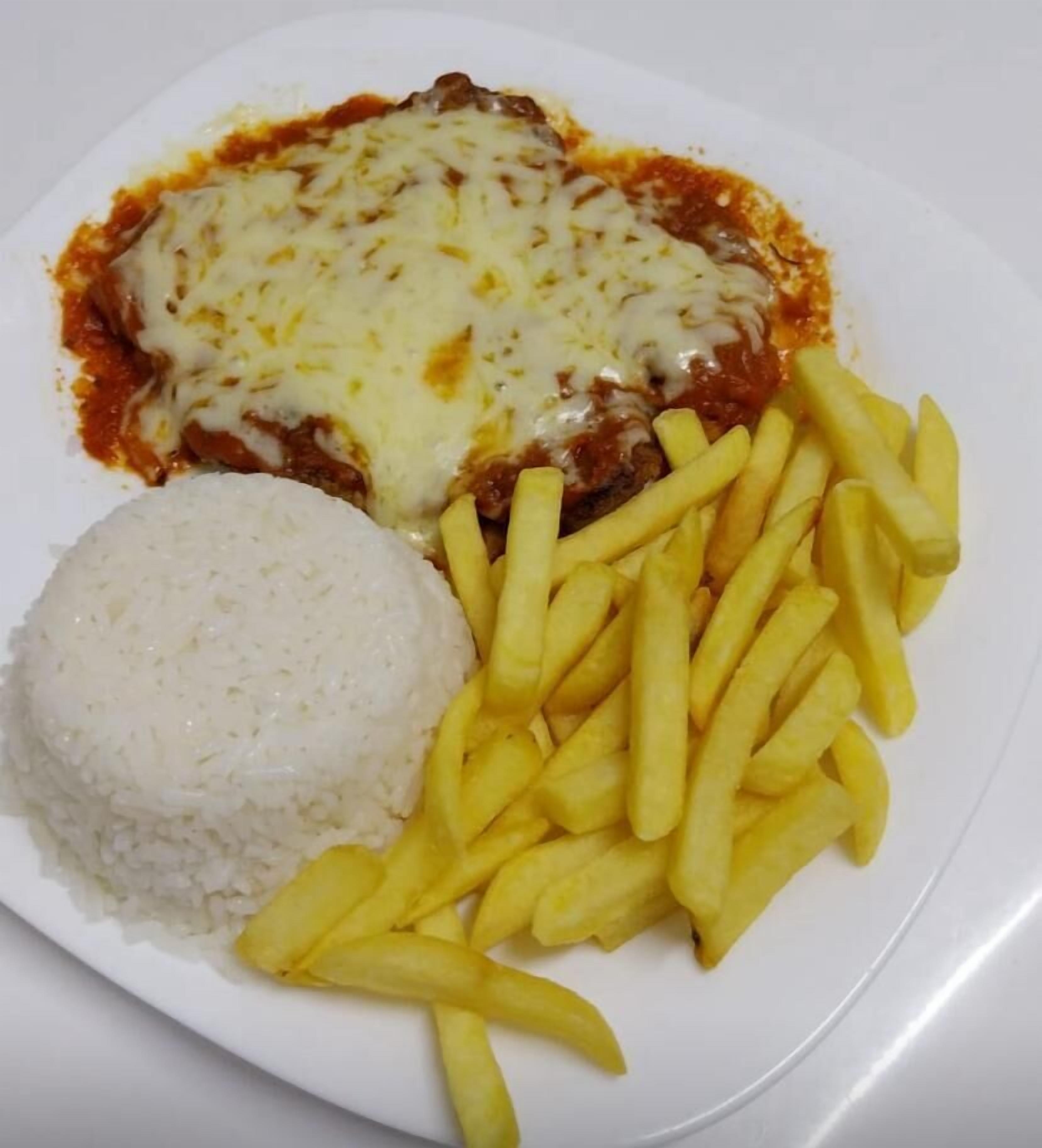 Un plato con una porción de pasta cubierta de queso, arroz y una guarnición de papas fritas.