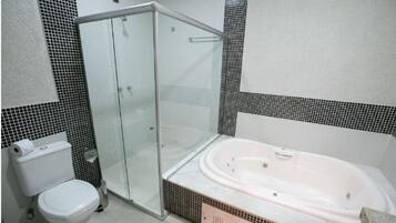 Un baño con ducha acristalada, inodoro blanco y una bañera grande.