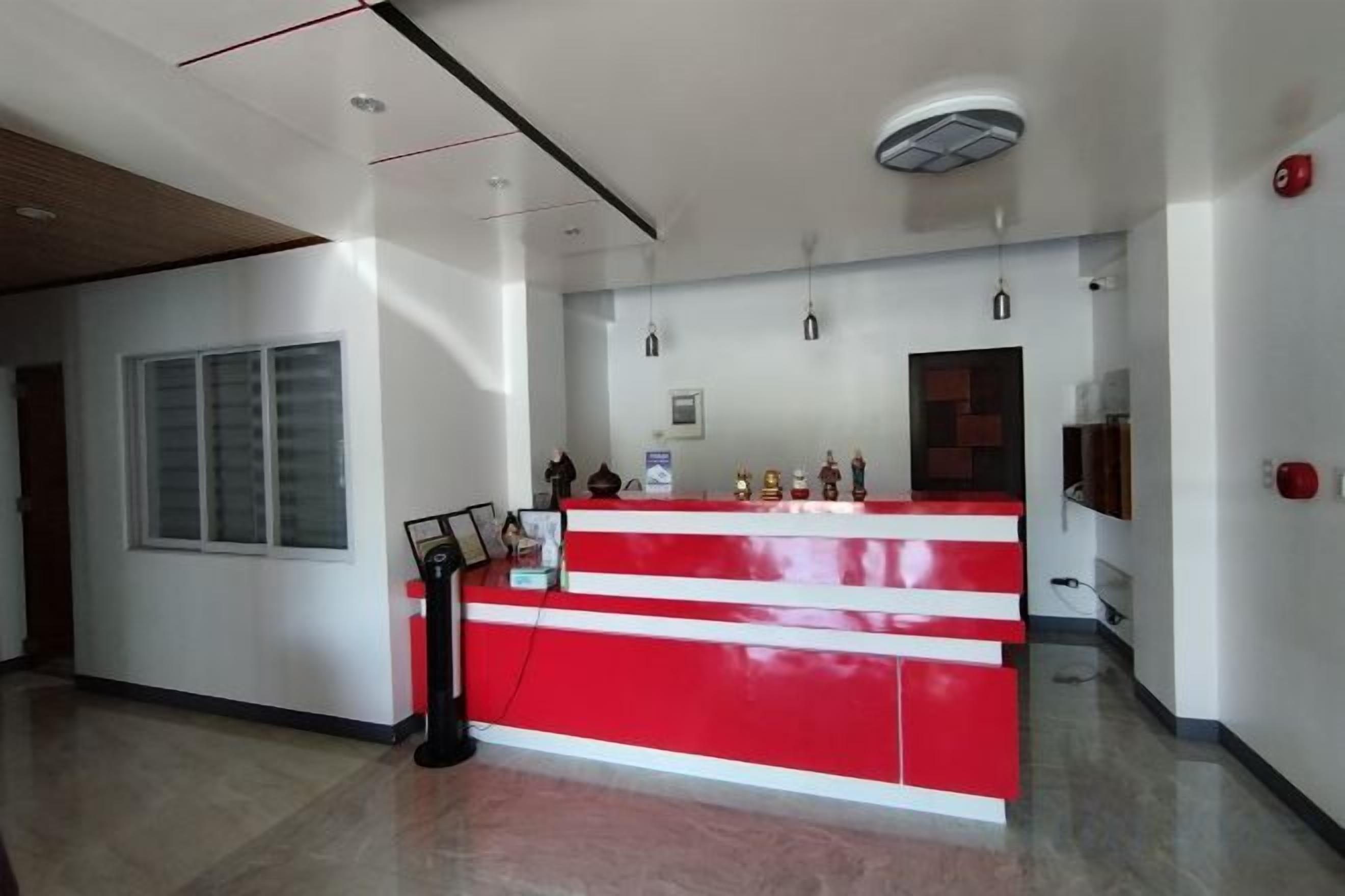 A reception area with a red counter, a window, and a fire alarm.