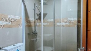 A bathroom with a glass-enclosed shower, a toilet, and a sink.