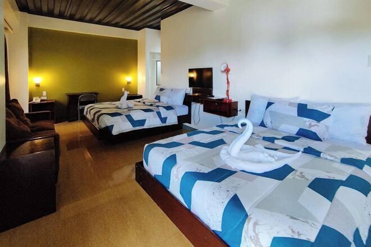 Ein Hotelzimmer mit zwei Betten, einem Schlafsofa, einem Schreibtisch und einem Fernseher.