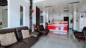 A modern hotel lobby with a reception desk, leather sofas, and a Christmas tree.