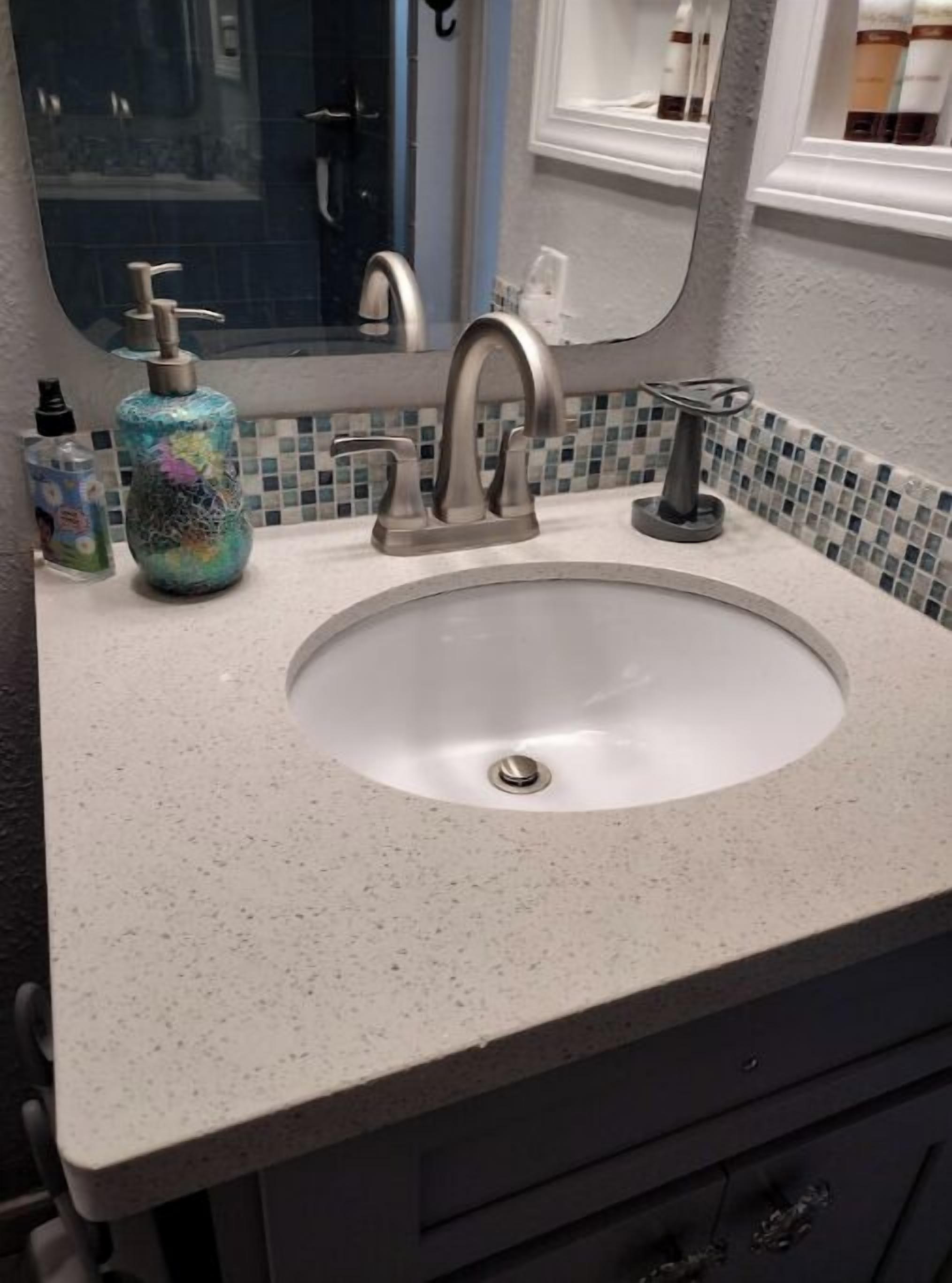 A bathroom sink with a modern faucet, a mirror above it, and a tiled backsplash.