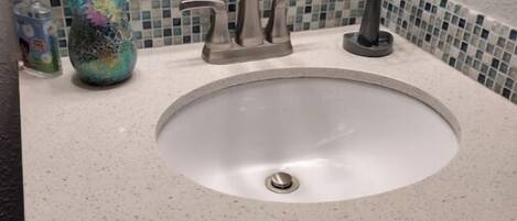 A bathroom sink with a modern faucet, a mirror above it, and a tiled backsplash.