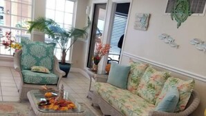 A living room with wicker furniture, a floral sofa, and a coffee table with decorative items. - EndlessWaves Oceanfront Gulf View Resort 2 Pools (Galveston)