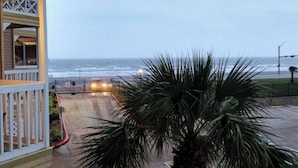 A beachfront property with a view of the ocean, a gated entrance, and a palm tree in the foreground. - EndlessWaves Oceanfront Gulf View Resort 2 Pools (Galveston)