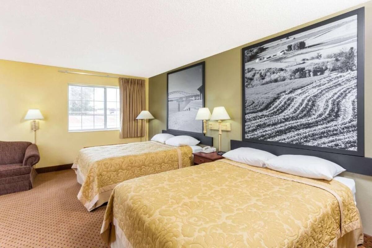 A hotel room with two beds, a sofa, and a large black and white photograph on the wall.