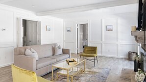 Una sala de estar moderna con un sofá beige, un sillón amarillo y una mesa de centro de vidrio.