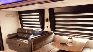 A cozy RV interior with a sofa, a small table, and a window with blinds.